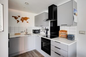 Una cocina moderna con armarios blancos, una campana extractora negra y un mapa mundial en la pared.