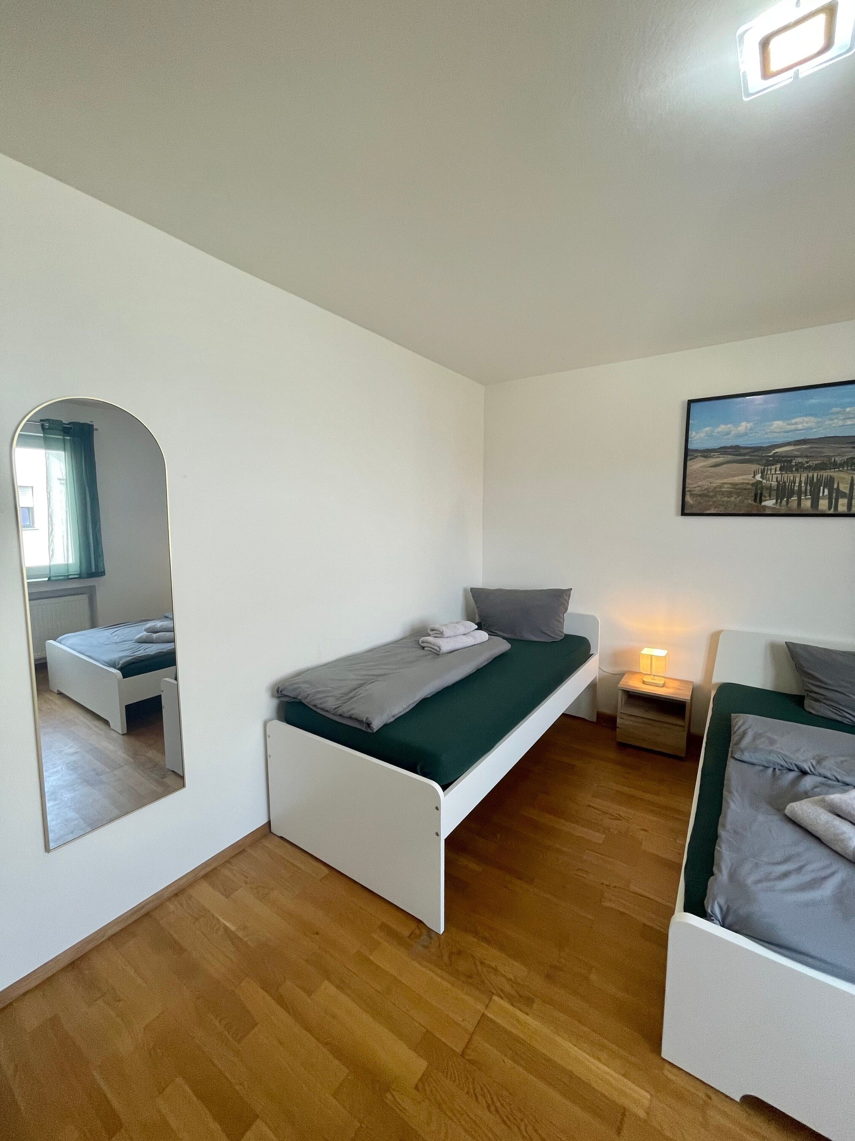 Un dormitorio con una cama individual, una mesita de noche, un espejo y un cuadro en la pared.