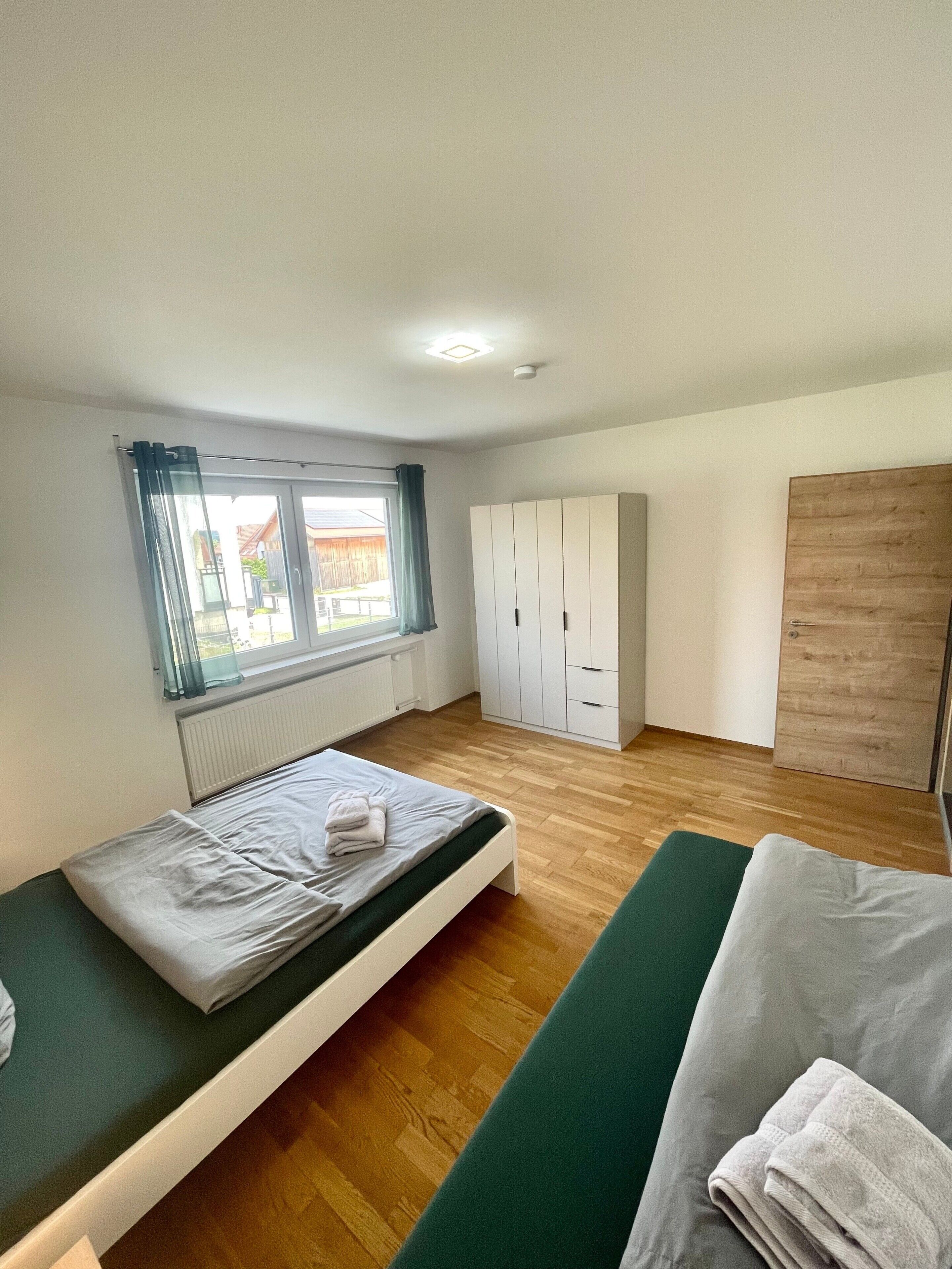 A room with a bed, a wardrobe, a radiator, and a window with curtains.