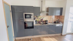 Una cocina moderna con armarios grises, microondas integrado, horno y lavavajillas.