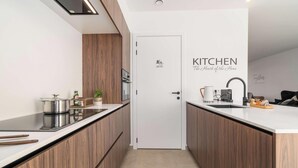 Une cuisine moderne avec des meubles en bois, un plan de travail blanc et une casserole en acier inoxydable.