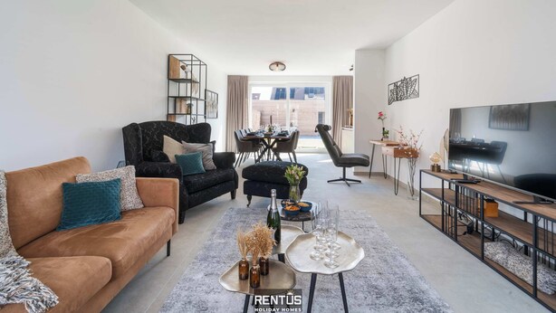 Un salon moderne comprenant un canapé, une table basse, un téléviseur et un coin repas.