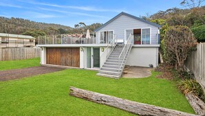 A two-story house with a visible staircase leading to the upper floor, a fenced backyard, and a driveway. - Beach House (Separation Creek)