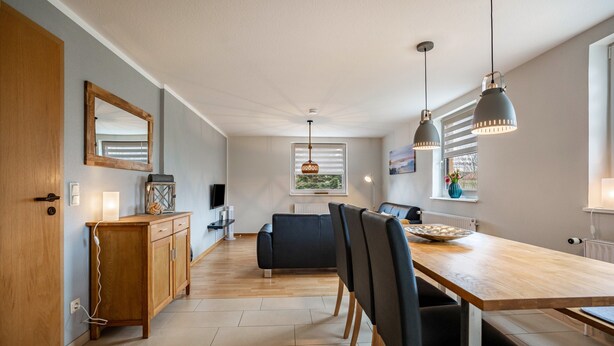 A modern kitchen with a wooden dining table, black chairs, and pendant lights. - Apartment 'Strandläufer' with Shared Garden and Wi-Fi (Westerholz)