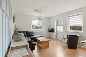 Un salon moderne avec un canapé, une table basse et un téléviseur.