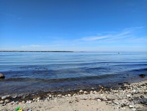 Une mer calme, avec une côte rocheuse et des éoliennes visibles au loin.