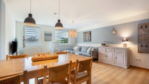 Une cuisine moderne avec une table à manger, des chaises, des luminaires suspendus, un canapé et un meuble de rangement.
