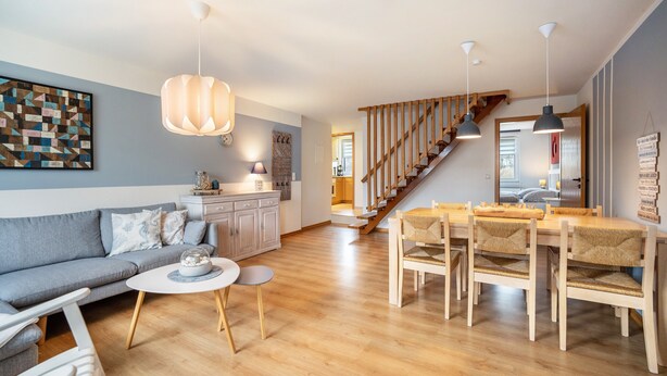 Un salon moderne comprenant un canapé, une table à manger et des chaises, un escalier et un coin cuisine.