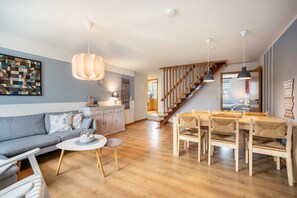 Un salon moderne comprenant un canapé, une table à manger et des chaises, un escalier et un coin cuisine.