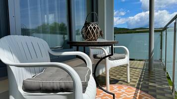 Un balcon avec des chaises blanches, une petite table et un objet décoratif.