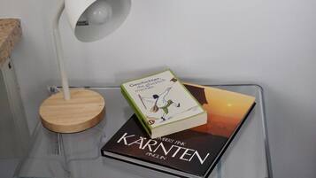 A book titled 'Kärnten' by Albert Fink on a clear glass table, a white lamp with a wooden base, and a partial view of a textured wall.