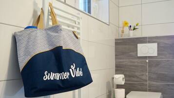 Een badkamer met een handdoekhouder, een decoratieve tas, een toilet en een lichtschakelaar aan de muur.