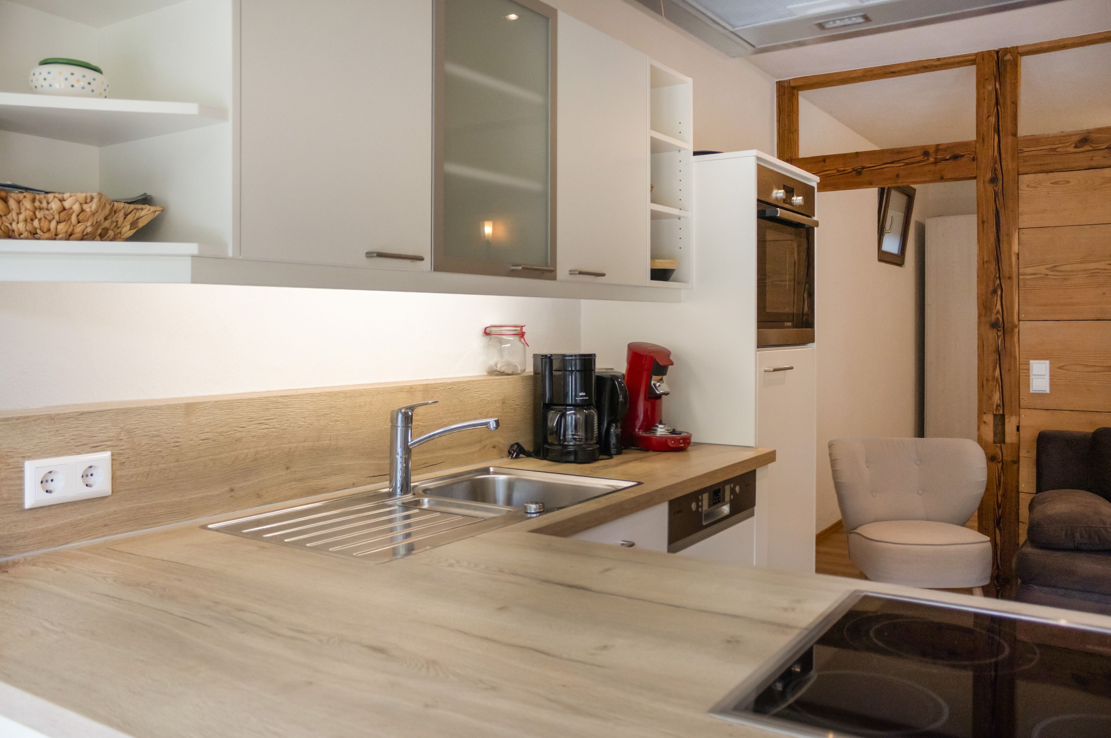 A modern kitchen with a wooden countertop, stainless steel sink, and a built-in oven.