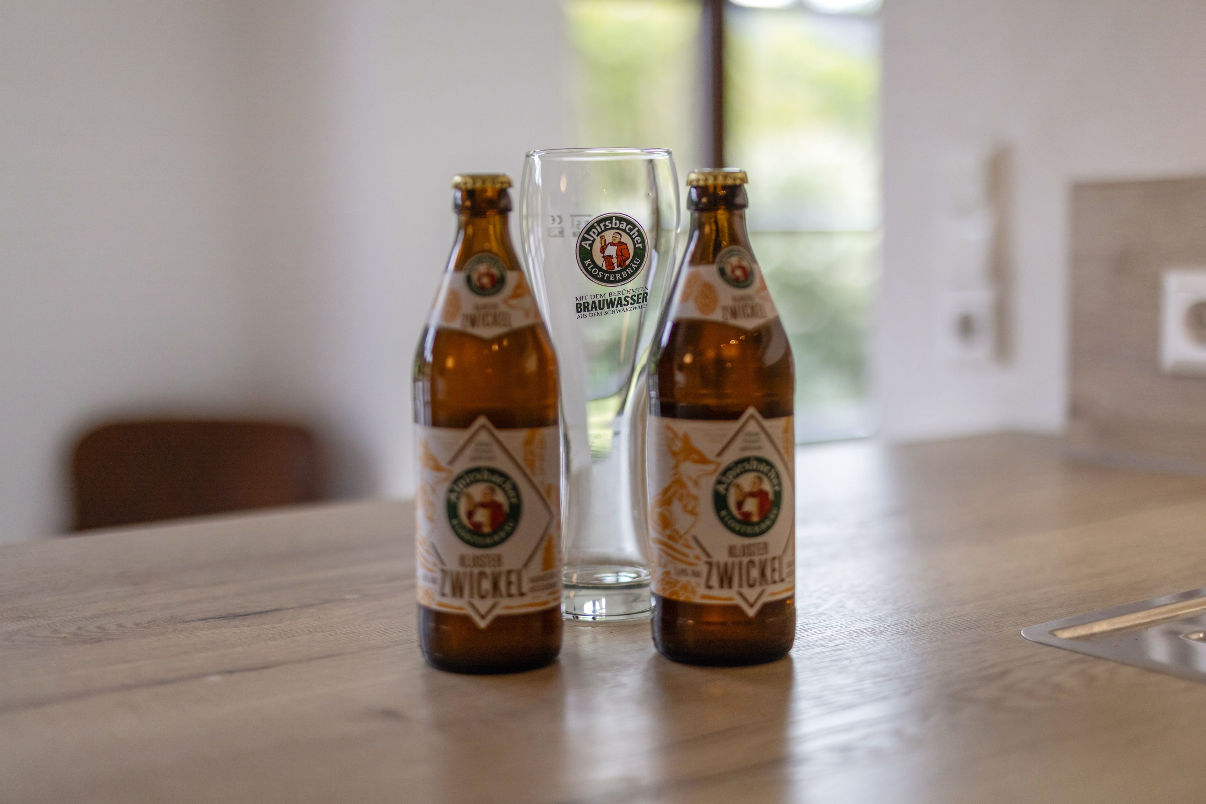 Dos botellas de cerveza y un vaso sobre una mesa de madera.