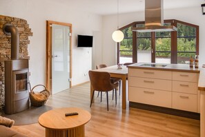 A modern kitchen with a large window, a dining area with a table and chairs, and a fireplace.
