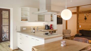 Una cocina moderna con armarios blancos, una isla central y un comedor con mesa de madera.