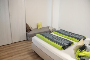 A bedroom with a bed, a bench, and a wardrobe.