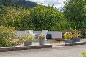 An outdoor seating area with a table and chairs, surrounded by potted plants and a decorative fire bowl. - Ferienwohnung Maulbetsch with Private Terrace, Garden, and Fireplace (Alpirsbach)
