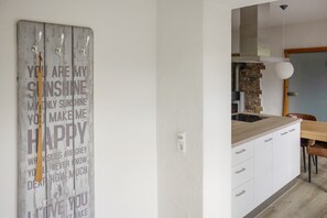 A modern kitchen with a wooden island, white cabinets, and a stone backsplash.