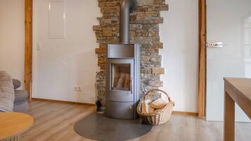 A modern living room with a stone wall, a built-in wood stove, and a wicker basket on the floor.