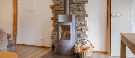 A modern living room with a stone wall, a built-in wood stove, and a wicker basket on the floor.