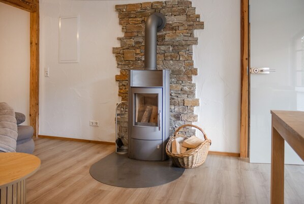 Una sala moderna con una pared de piedra, una estufa de leña integrada y una cesta de mimbre en el suelo.