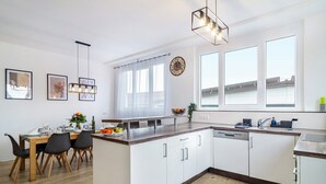 A modern kitchen with white cabinets, a wooden countertop, and a dining area with a table and chairs. - Holiday Apartment 'Mäxle's Loft' with Shared Garden and Wi-Fi (Fluorn-Winzeln)