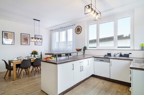 Una cocina moderna con armarios blancos, una encimera de madera y un comedor con mesa y sillas.