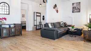 A modern living room with a sectional sofa, a wooden cabinet, and a dining area with a table and chairs. - Holiday Apartment 'Mäxle's Loft' with Shared Garden and Wi-Fi (Fluorn-Winzeln)