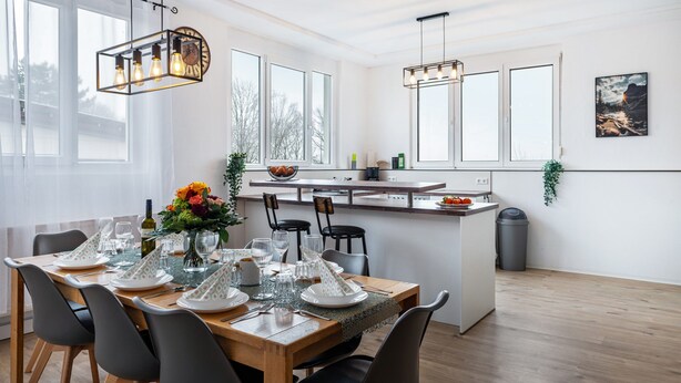 A modern kitchen with a dining area, large windows, and a view of the outdoors. - Holiday Apartment 'Mäxle's Loft' with Shared Garden and Wi-Fi (Fluorn-Winzeln)