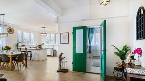 A spacious living area with a dining table, kitchen, and open green door leading to another room. - Holiday Apartment 'Mäxle's Loft' with Shared Garden and Wi-Fi (Fluorn-Winzeln)