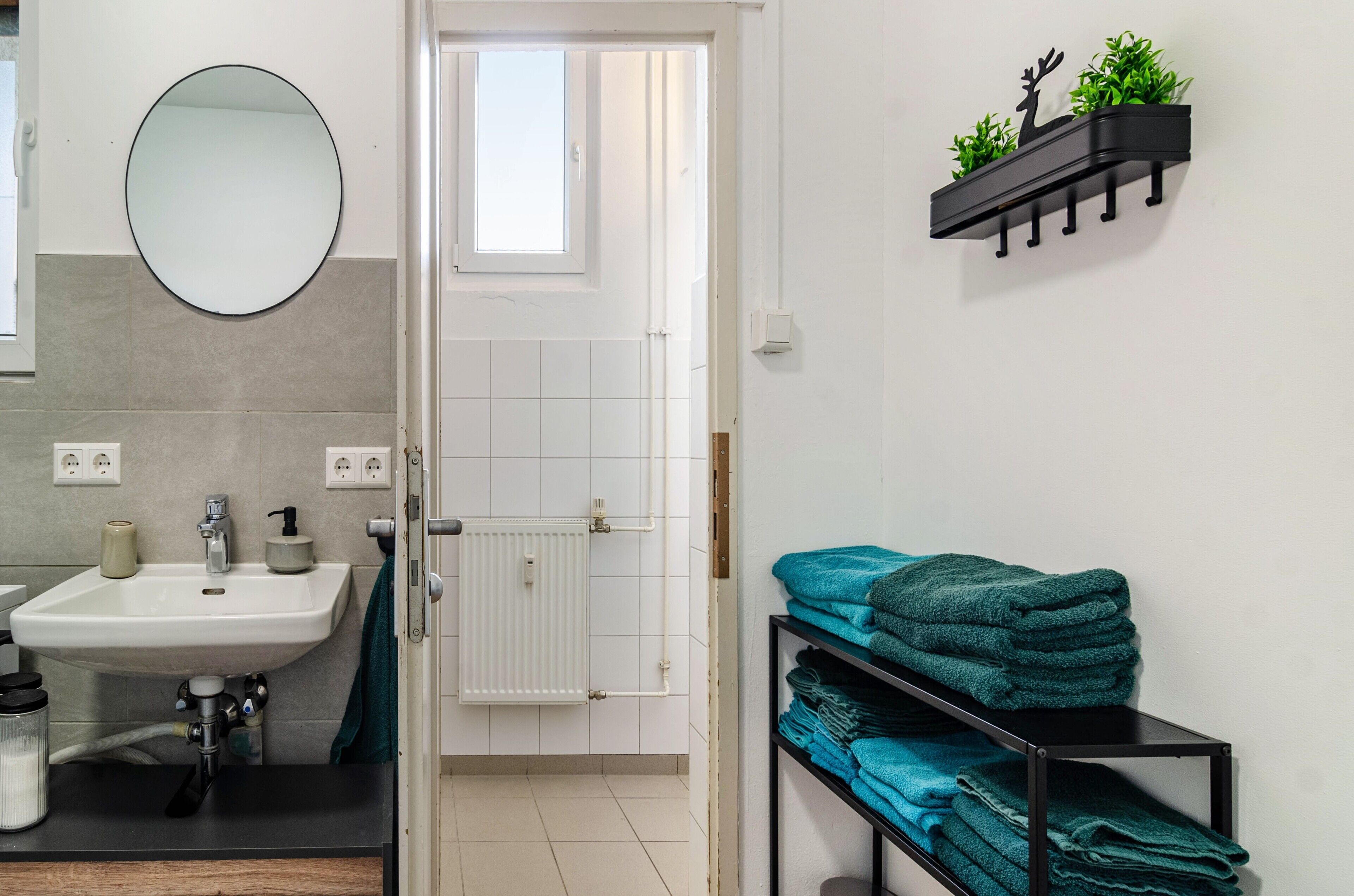Une salle de bain équipée d’un lavabo, d’un miroir, d’un porte-serviettes et d’une porte donnant sur une autre pièce.