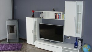 A modern living room with a flat-screen TV, white entertainment unit, books, a globe, and a small table. - Apartment 'Schopper' with Balcony and Wi-Fi (Halblech)