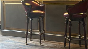 A bar area with two leather chairs, a coffee machine, and shelves with glassware. - Viareggio Old Style Sea View (Viareggio)