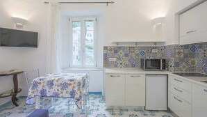 Une cuisine compacte avec un plan de travail recouvert de carreaux, un four à micro-ondes et un petit évier.