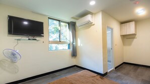 A room with a flat-screen TV mounted on the wall, an air conditioning unit, a window with curtains, a door, and a small cabinet. - Green Field Mountain Villa (Taoyuan City)