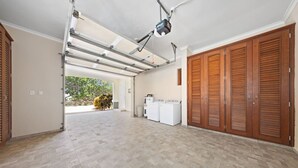 Une buanderie spacieuse équipée d’un projecteur fixé au plafond, de meubles en bois et offrant une vue sur la verdure environnante.