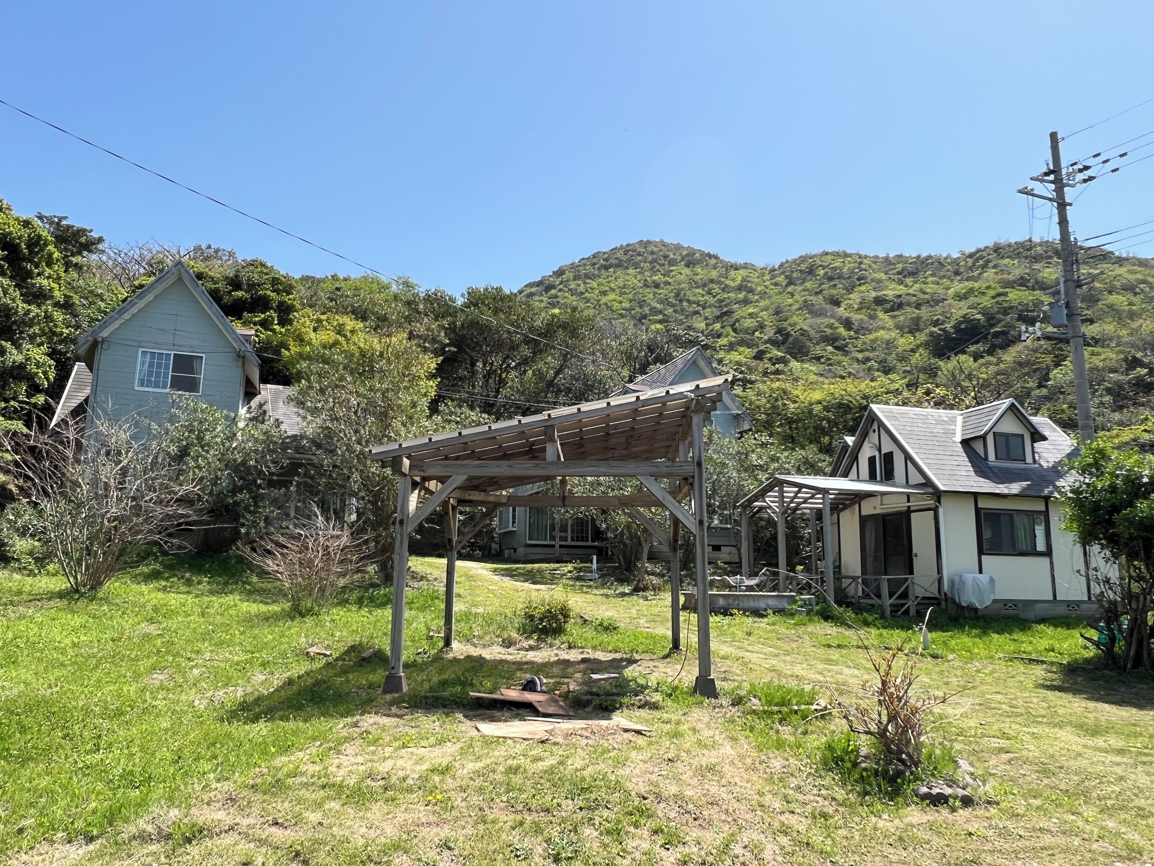 A rural house with a wooden pergola in the yard.