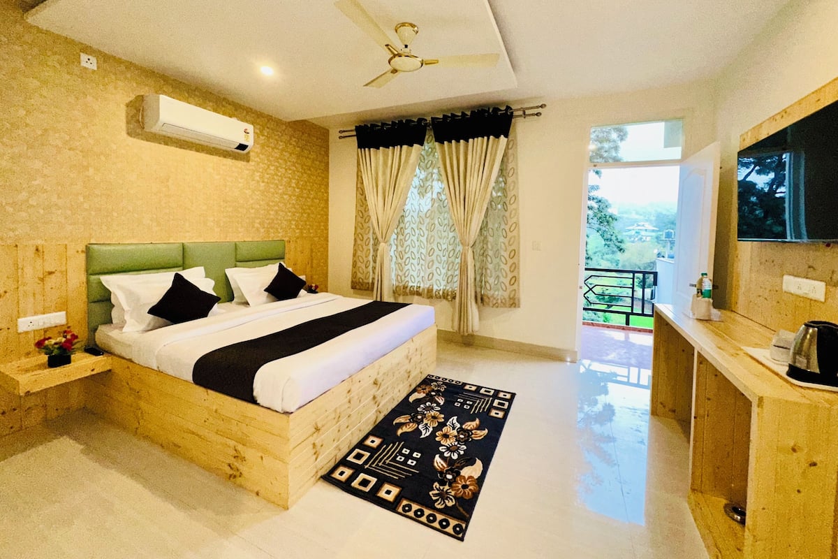 A bedroom with a bed, a ceiling fan, a window with curtains, a TV, and a wooden desk.