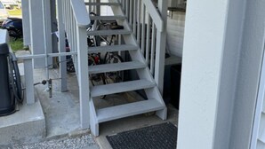 A set of outdoor stairs leading to a covered porch area with a bicycle rack. - The Mast at Soundview · Beach+Ocean+Sunrise (Old Lyme)