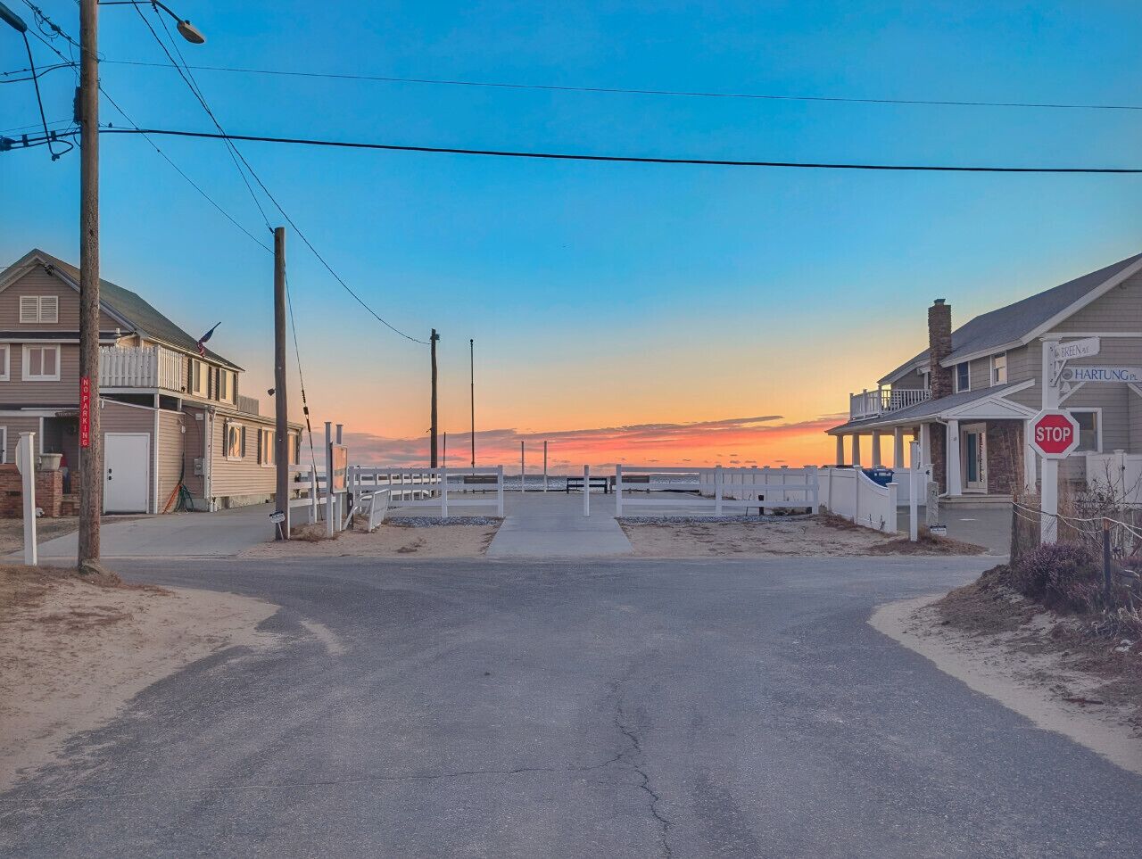 A coastal road with a stop sign, a beach, and beachfront properties.