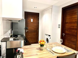 Cocina compacta con cafetera, lavabo y lavadora.