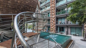 En moderne bygning med swimmingpool, en spiraltrappe og et palmetræ.