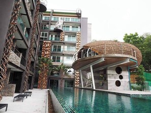 Un edificio moderno con piscina, que destaca por una estructura circular con techo de madera y una escalera en espiral.