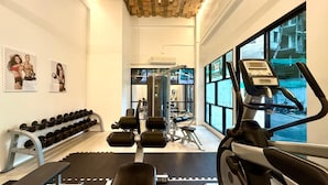 Et fitnesscenter med træningsudstyr, håndvægte og et løbebånd.