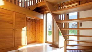 A wooden staircase leading to a second floor, a wooden door with a coat rack, and a view of the outside through a large window. - Rendeux Valley View Retreat (Rendeux-Beffe)