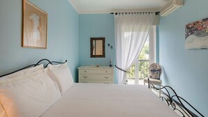 Een slaapkamer met een bed, een dressoir, een spiegel en een raam met gordijnen.