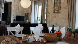 A dining area with a stone wall, a television, and a painting of a cat by a window. - Villa in Languedoc with Pool near Historic Cities (Rousson)