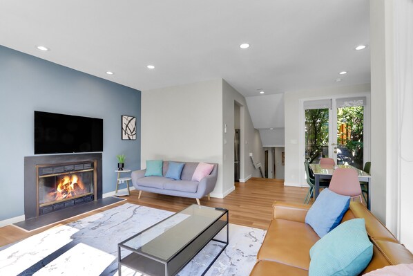 A modern living room with a fireplace, a sofa, a coffee table, and a TV.