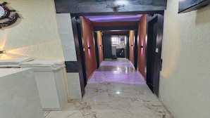Un pasillo con suelo de mármol, puertas de madera e iluminación morada.